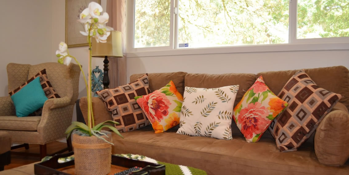 Beige couch with colorful floral pillows.